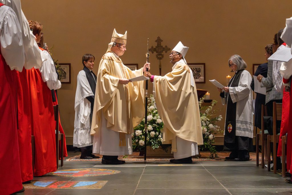 Bishop Michael Curry hands a ceremonial crosier to Bishop Sean Rowe at the latter's investiture as Presiding Bishop