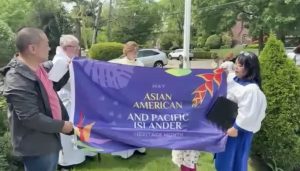 James and Chisako hold the AAPI Heritage Month flag prior to it being raised on the flagpole.